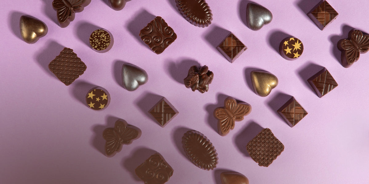Charles Chocolates confections scattered on a lavender background