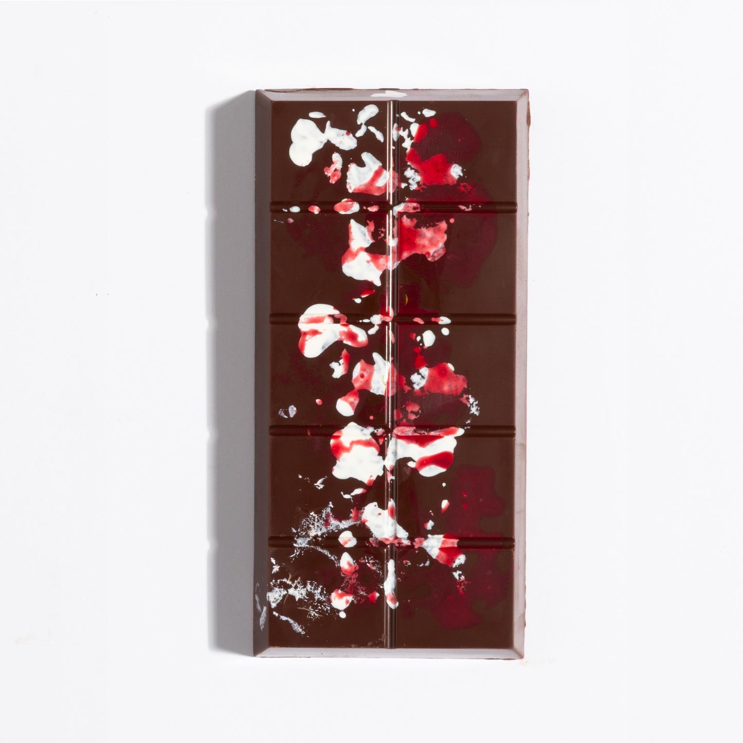 Unwrapped Pecan French Praline Crunch Bar with red cocoa butter splatter on dark chocolate