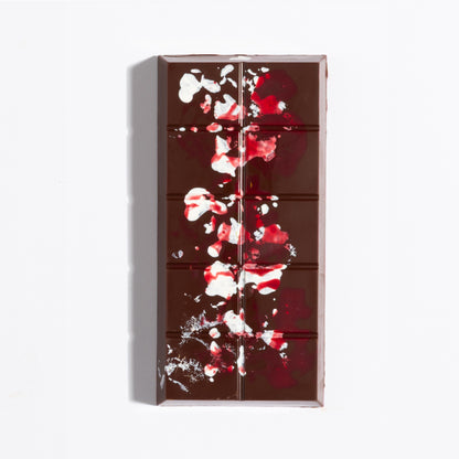 Unwrapped Pecan French Praline Crunch Bar with red cocoa butter splatter on dark chocolate